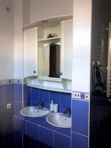 Baño azul y blanco con 2 lavabos y espejo en Prutets Guest House, en Tatariv