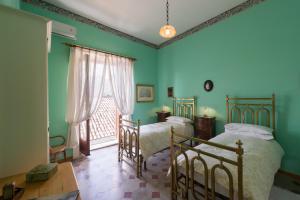 two beds in a room with green walls and a window at Dimora del Prete di Belmonte in Venafro