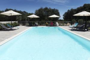 a pool with chairs and umbrellas in it at Hôtel Des Nacres in Ventiseri