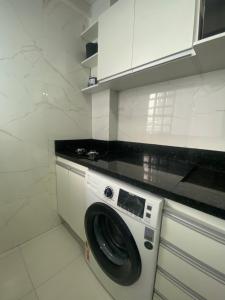 a washing machine in a kitchen with white cabinets at Flat completo no centro de Belém in Belém