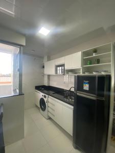La cuisine est équipée d'un réfrigérateur noir et d'un lave-vaisselle. dans l'établissement Flat completo no centro de Belém, à Belém