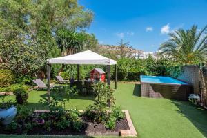 a garden with a white umbrella and a swimming pool at XPCE Gibralfaro Gardens in Málaga