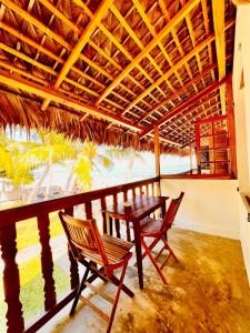 einen Tisch und Stühle auf einem Balkon mit Meerblick in der Unterkunft L'Ylang Ylang Auberge d'AMBATOLOAKA in Ambatoloaka