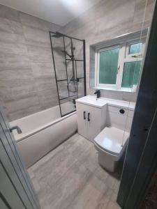 a bathroom with a toilet and a tub and a window at 3 Bed Detached House & Hot Tub in Wrexham