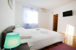 1 dormitorio con 1 cama blanca y 1 silla azul en Apartments Martina, en Zadar