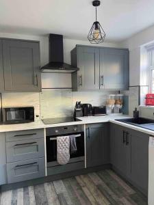 a kitchen with stainless steel appliances and gray cabinets at Modern and Comfy House, Sky sports, PS3 in Gateshead