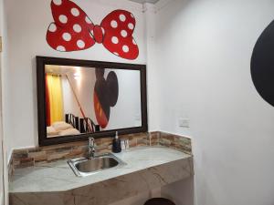 ein Badezimmer mit einem Waschbecken und einem Spiegel mit Schmetterlingen in der Unterkunft Wally World Inn in Comayagua