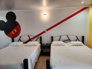 2 Betten in einem Zimmer mit einem roten Streifen an der Wand in der Unterkunft Wally World Inn in Comayagua