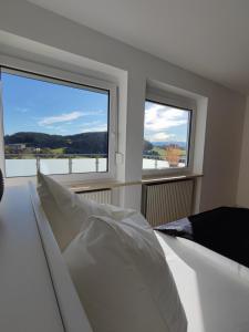 にあるFerienhaus Alpenblickのベッドルーム1室(ベッド1台、窓2つ付)