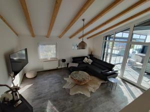 a living room with a black couch and a tv at Ferienhaus Alpenblick in Ermengerst