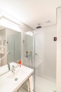 a white bathroom with a sink and a shower at Hotel Moov Porto Alegre in Porto Alegre