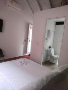 ein weißes Schlafzimmer mit einem Bett und einem WC in der Unterkunft EMMA HOTEL SAN DIEGO in Cartagena de Indias