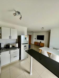 a kitchen with white cabinets and a black counter top at Departamentos Leloir in Neuquén