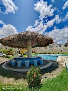 a large straw umbrella with chairs and a pool at Hermosa casa a un paso del mar! in La Sabana