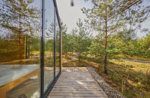a glass house in the woods with a wooden walkway at Forestic Lietuva in Vilionys