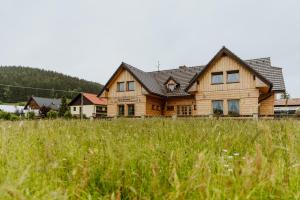 una gran casa de madera en un campo de hierba en Apartmány Velké Karlovice, en Velké Karlovice