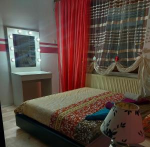 una camera da letto con un letto con tende rosse e una finestra di Quattro apartment a Zaječar