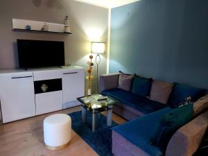 un salon avec un canapé bleu et une télévision dans l'établissement Quattro apartment, à Zaječar
