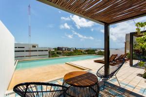 eine Terrasse mit einem Tisch, Stühlen und einem Pool in der Unterkunft Riva Condos by The Spot Rentals in Playa del Carmen