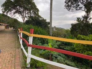 uma cerca vermelha e amarela ao lado de uma estrada de tijolos em DinoAgro Potrero Grande em Moniquirá