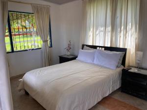 una camera da letto con un letto con lenzuola bianche e una finestra di DinoAgro Potrero Grande a Moniquirá