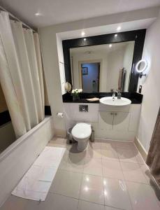 a bathroom with a toilet and a sink and a mirror at LondonEYE private bedroom in shared flat in London
