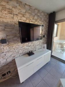a living room with a tv on a stone wall at appartement les pieds dans l'eau in Cannes
