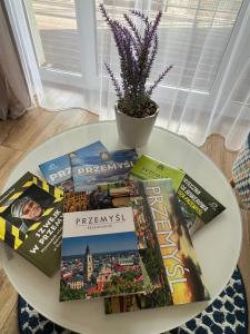 a white table with books and a plant on it at Apartament Alexa na Tatarskiej A in Przemyśl