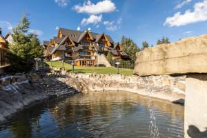 ein großes Haus mit einem Teich davor in der Unterkunft Mountain Base - Rezydencja Górski Potok Premium in Kościelisko