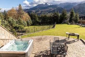 einen Whirlpool auf einer Terrasse mit einem Tisch und Stühlen in der Unterkunft Mountain Base - Rezydencja Górski Potok Premium in Kościelisko