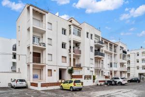 ein Mehrfamilienhaus mit auf einem Parkplatz geparkten Autos in der Unterkunft WELCS APARTAMENTO 105 EMP cerca del mar in Empuriabrava