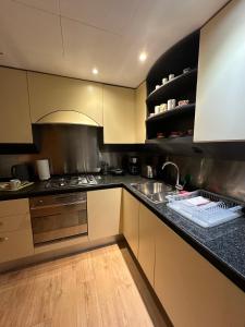 a kitchen with a sink and a stove at Canary Wharf 1 bed apartment in London