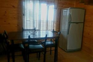 a kitchen with a wooden table and a refrigerator at Linda Cabaña con Vista al Mar a Pasos de la Playa in La Ligua