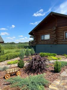 a garden with a log cabin with a wagon in front of it at VIP ШАЛЕ ТИША in Shirokaya Greblya