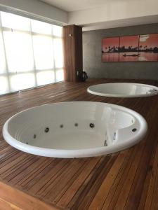 Eine große weiße Badewanne steht auf einem Holzboden. in der Unterkunft Flat Por Temporada no Edifício Time Maceió-AL in Maceió