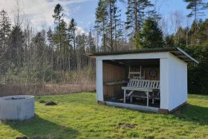 a white shed with a bench in the grass at Nyhem stugan in Våxtorp