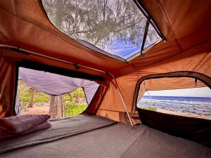 a tent on the beach with a view of the ocean at Embark on a journey through Maui with Aloha Glamp's jeep and rooftop tent allows you to discover diverse campgrounds, unveiling the island's beauty from unique perspectives each day in Haiku