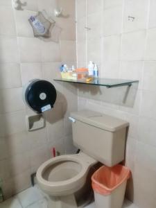 a bathroom with a toilet with a glass shelf above it at Casa céntrica antigua completa in Orizaba