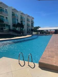 a swimming pool with two metal handles in the water at Mar e sol residencial 2 quartos com ar condicionado,500 metros da praia de Jacumã in Conde