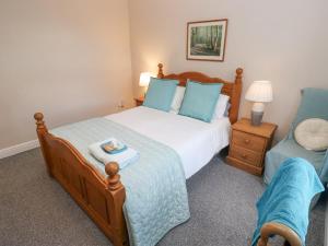 a bedroom with a large bed and a chair at Bluebell Cottage in Selby