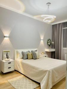 a white bedroom with a large bed and a white dresser at ЖК Homeland EXPO 2 комн in Taldykolʼ