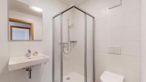 ein weißes Bad mit einer Dusche und einem Waschbecken in der Unterkunft Spacieux appart 3,5 pièces incl Jaccuzzi Privé in Leukerbad