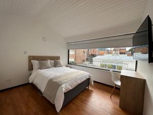 a bedroom with a bed and a large window at One Fourteen Rooms in Bogotá