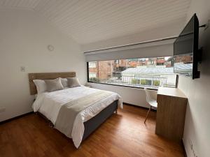 a bedroom with a large bed and a large window at One Fourteen Rooms in Bogotá