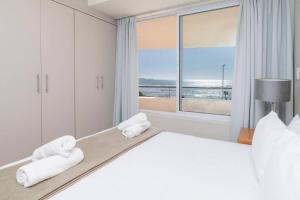 a bedroom with a bed with towels on it at Oceanfront Residence in Lagoon Beach in Cape Town