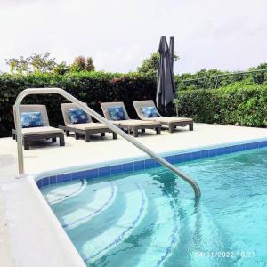 einen Pool mit 2 Stühlen und einem Sonnenschirm in der Unterkunft 3 bedrooms luxurious pool house centrally located close to everything in Saint Philip