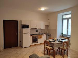 a kitchen with a table and a white refrigerator at Mi'Ele Apartments in Pergine Valsugana