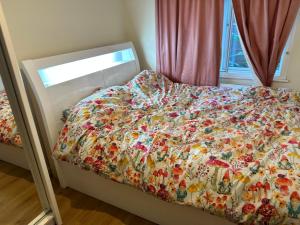uma cama com um edredão florido num quarto em Cool &cosy em Londres