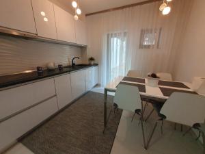 cocina con armarios blancos, mesa y sillas en Vila Vati - Arena Pitesti en Piteşti
