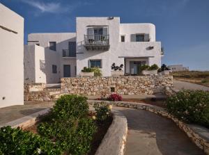 a large white building with a stone wall at Amelie Villa with pool and amazing sea views, Paros in Márpissa